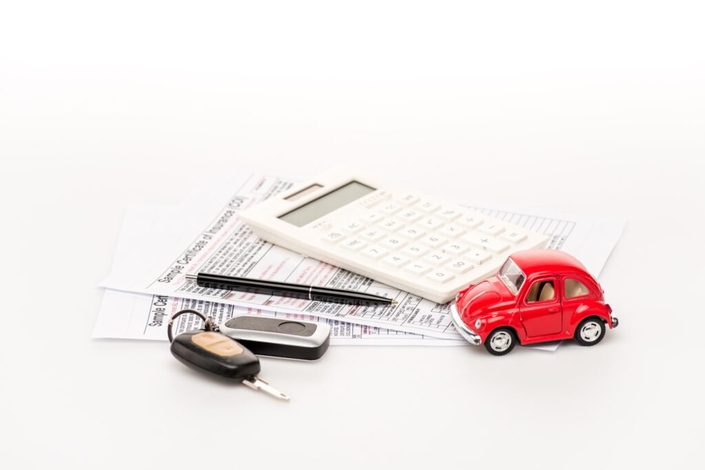 keys calculator insurance certificates and red toy car on white surface